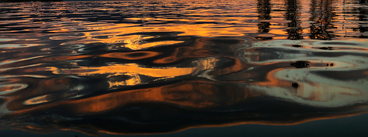 A colorful Montana sunset is reflected in the ripples of Flathead Lake