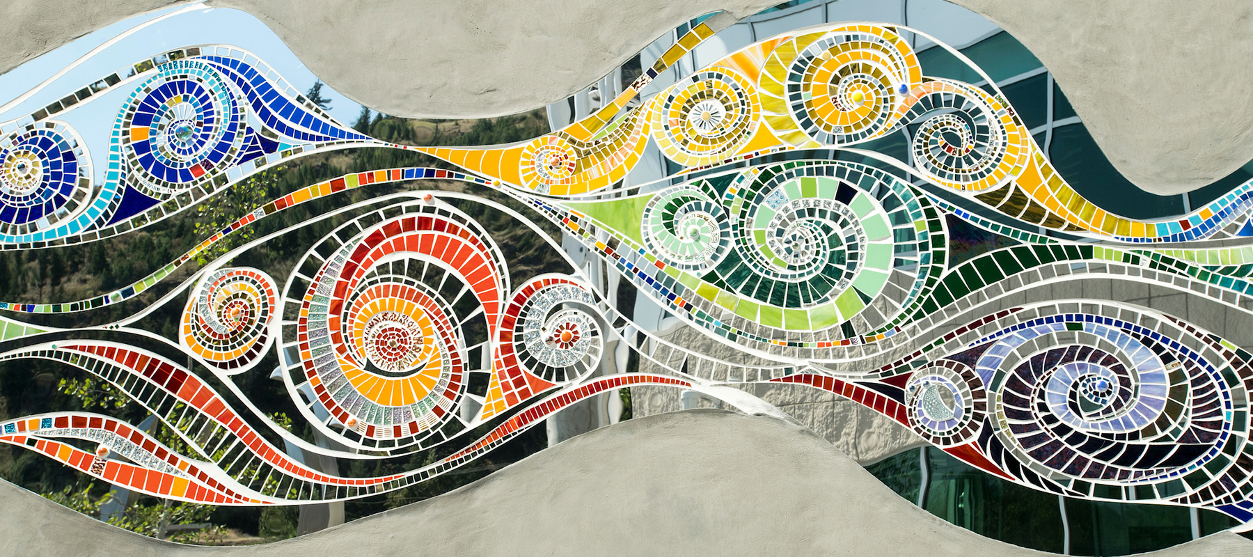 A mosaic mural of tile and mirrored pieces adorns the exterior of the Missoula College building. 